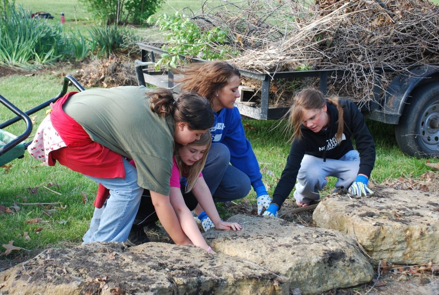 Baylee Wells and Mallory Schmidtlein help the fourth grade class at West Indianola clean out their fish pond for Earth day.  Members of NHS, Key Club and Interact all participated in the project.  (Photo by Emily Lehman)