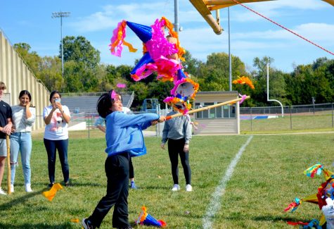 Members of World Culture Club wait for their turn while one of their members swings at the piñata.