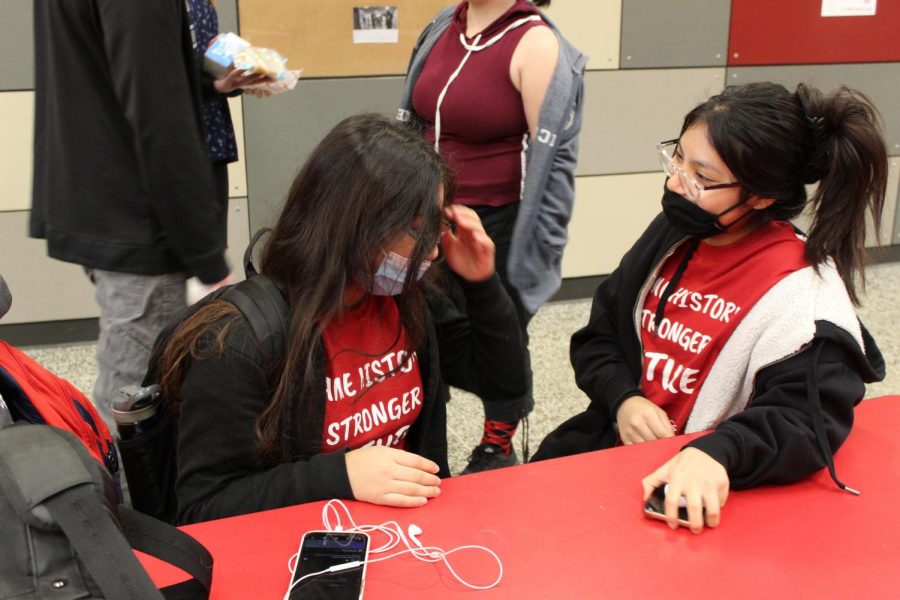 Senior Lilly Ruiz-Pineda talks to her friend in the lunchroom. Ruiz-Pineda wore a red shirt, stating, Same history, stronger future.