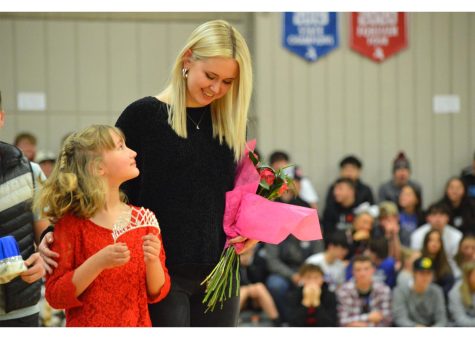 2021 Snowball Queen Ali Reed leads Natalie Miller, daughter of Mrs. Miller, down the basketball court to crown the 2022 Snowball Queen, Hannah Mott. 
