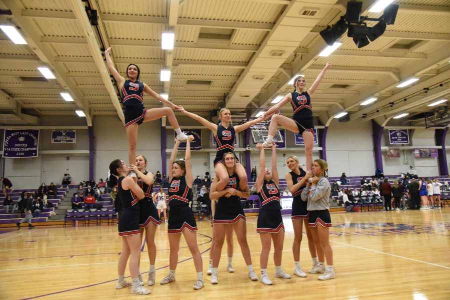 During the first quarter of the Jan. 28, 2022, game at Topeka West, the Seaman varsity cheerleaders perform a double hitch pyramid. This was the first time that junior Erin Feldkamp [pictured in the middle stunt, sitting on senior Kennedy Cook’s shoulders] flew in a stunt, but despite the nerves that taunted her, she and the rest of her team were able to display a flawless performance. “When I’m in the air I forget about the nerves or the people underneath,” Feldkamp explains.
