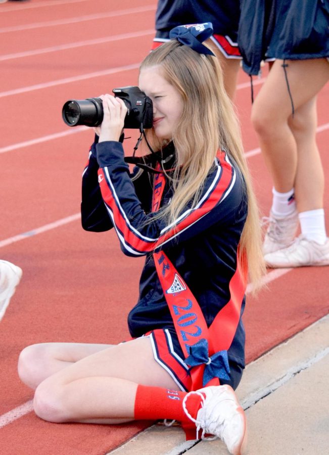 Senior Alyssa Boos focuses on taking photos of the fall senior night in October before cheering for the game. (2021-2022 Academic Runner-Up Photo)